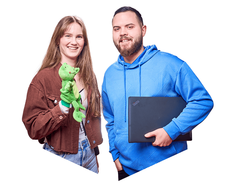 Eine Frau und ein Mann lächeln in die Kamera, während die Frau eine Froschhandpuppe trägt und der Mann einen Laptop in der Hand hat.