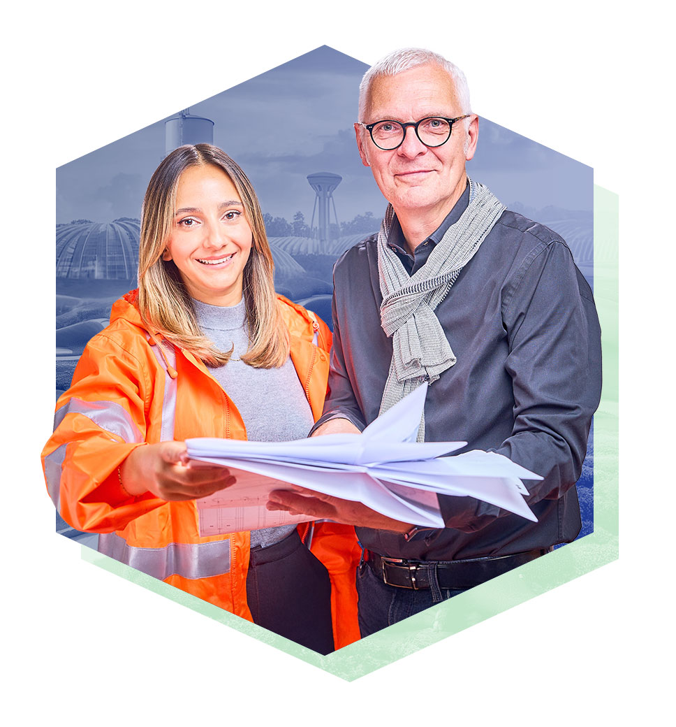 Eine Frau und ein Mann, die gemeinsam in die Kamera lächeln und mehrere Zettel in den Händen halten.