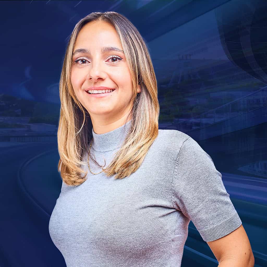 Eine Frau mit blonden Haaren lächelt in die Kamera vor einem futuristischen Hintergrund.