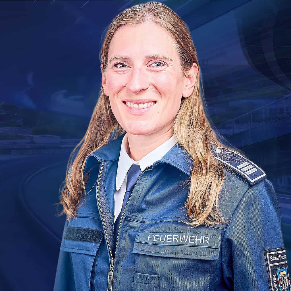 Lächelnde Frau mit langen blonden Haaren, die eine Feuerwehruniform trägt.