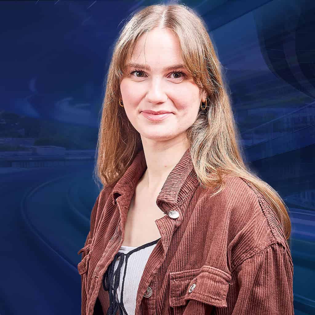 Lächelnde junge Frau mit langen blonden Haaren und einer braunen Jeansjacke.