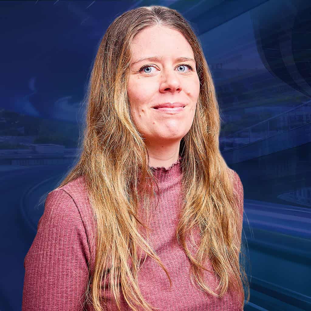 Eine Frau mit langen braunen Haaren lächelt in die Kamera vor einem futuristischen Hintergrund.