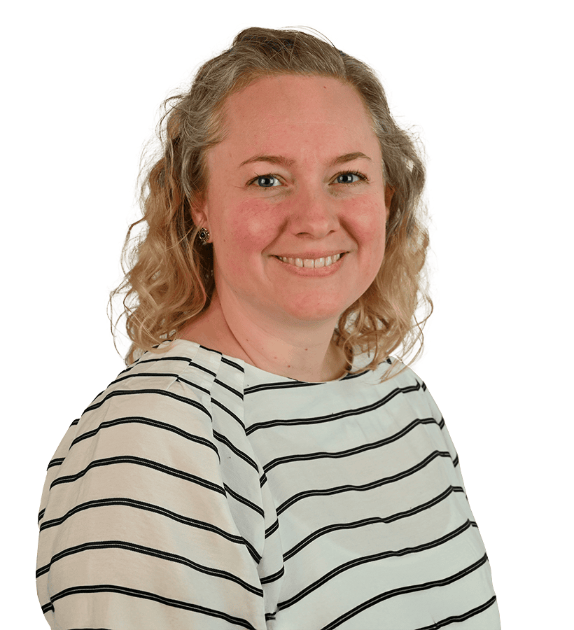 Eine lächelnde Frau mit kurzen gelockten blonden Haaren, die einen gestreiften Pullover trägt.