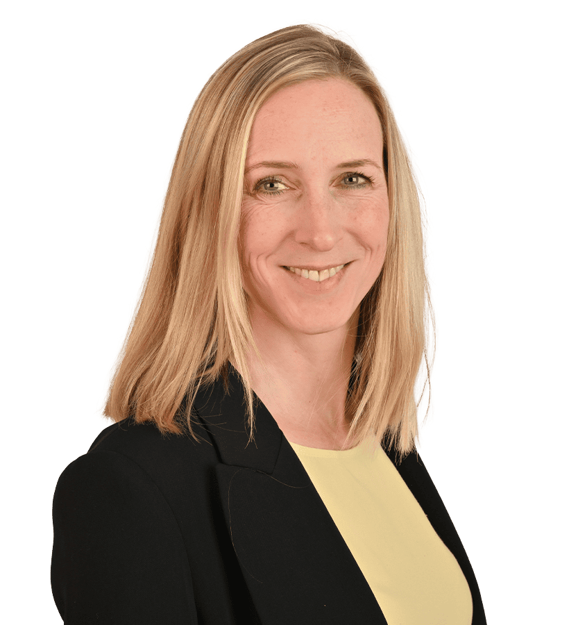 Eine lächelnde Frau mit blonden Haaren, die einen schwarzen Blaser trägt.