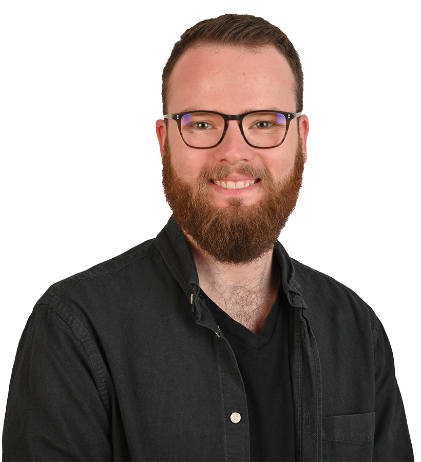 Ein Mann in einem schwarzen Hemd, der in die Kamera lächelt und eine Brille trägt.