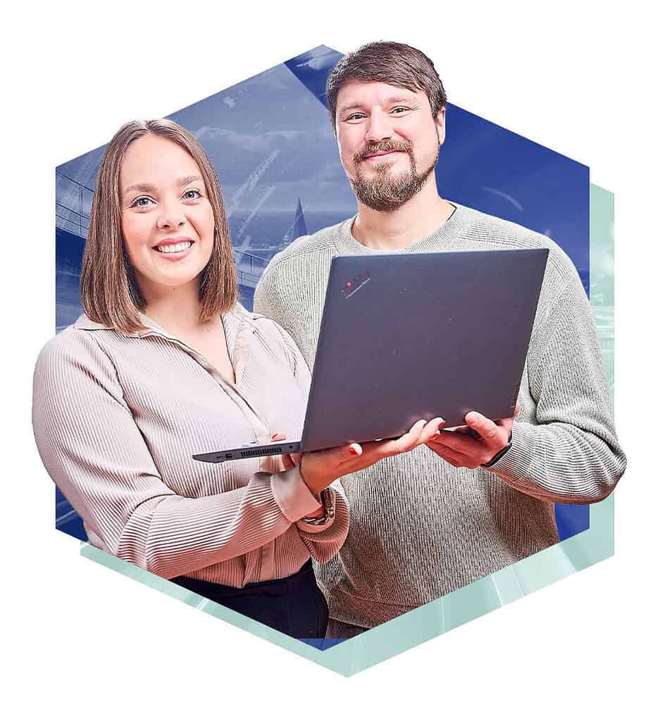 Ein lächender Mann und eine lächende Frau halten gemeinsam einen Laptop in der Hand.