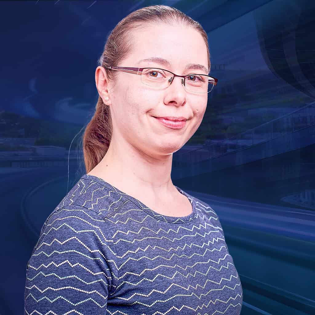 Lächelnde Frau mit einer Brille und einem Zopf.