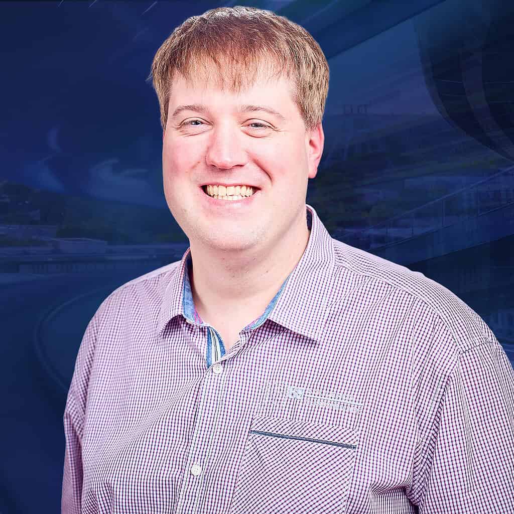 Lächender Mann mit Hemd vor blauem Hintergrund.